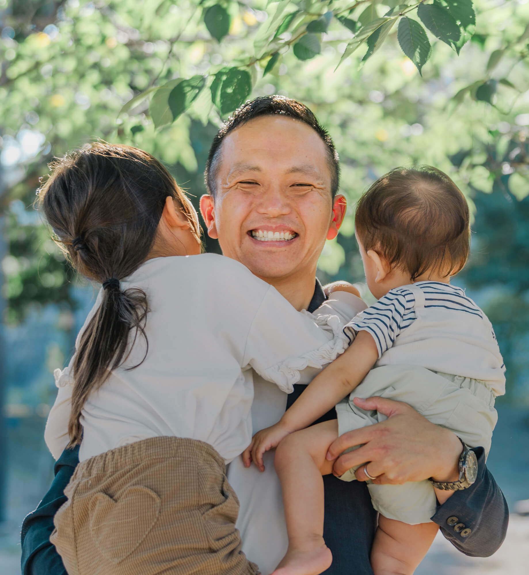 子ども二人を抱きかかえて微笑む中西勇太